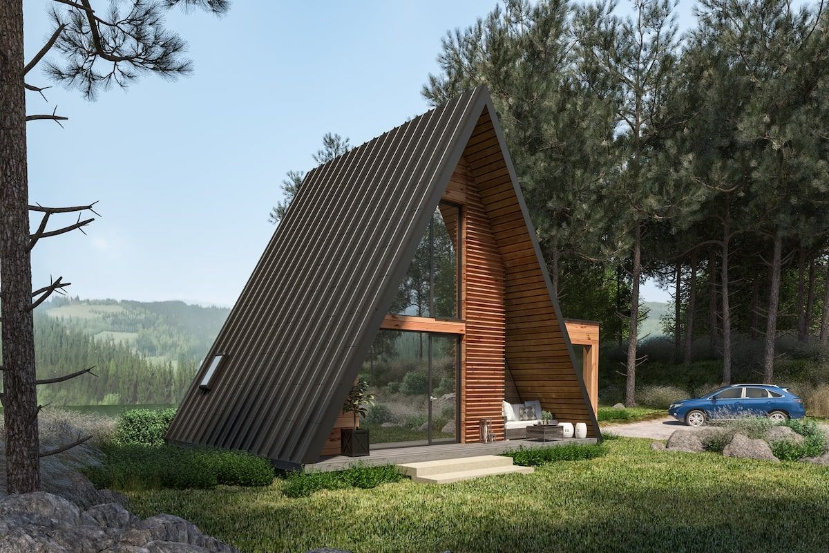 A-frame cabin with large windows in a forest setting, with a blue car parked nearby.