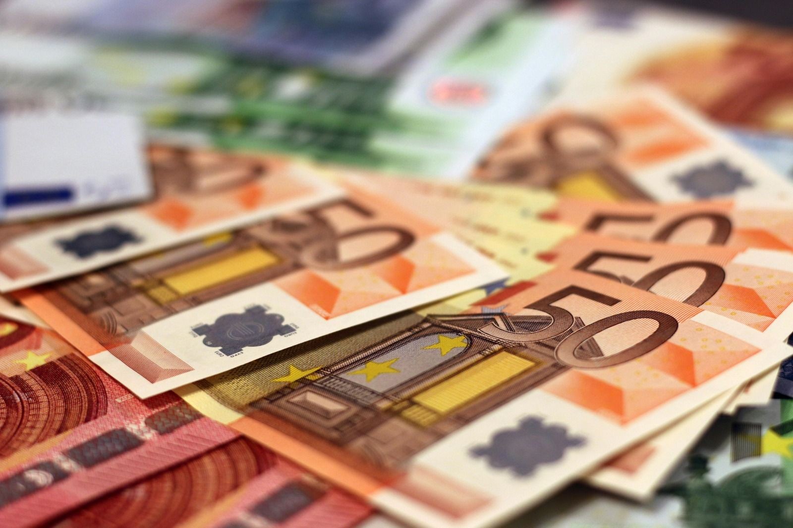 Close-up of multiple 50 euro banknotes scattered on a surface.