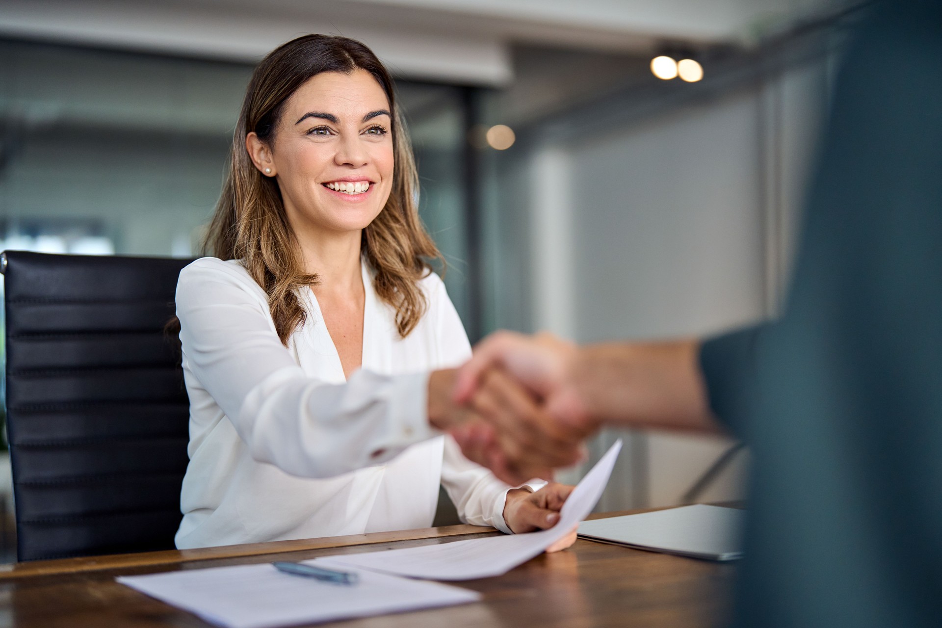 Poignée de main heureuse de la femme d’affaires d’âge moyen lors d’une réunion de bureau.